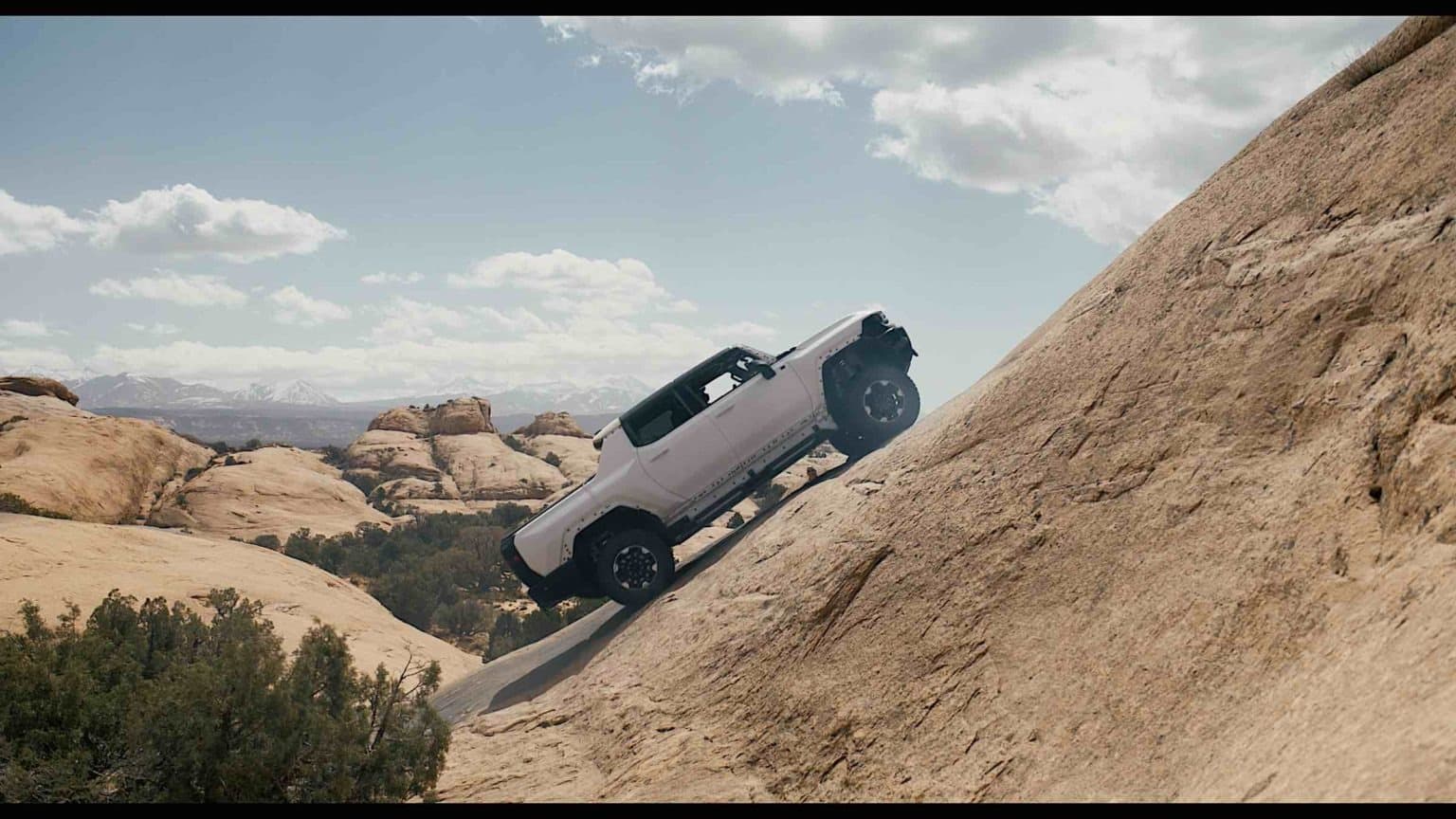 A GMC Hummer climbing the side of a steep hillside.