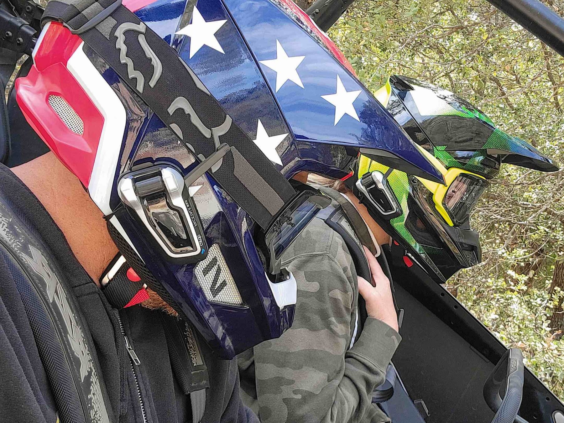 Two helmets equipped with Cardo Systems Packtalk Bold systems.