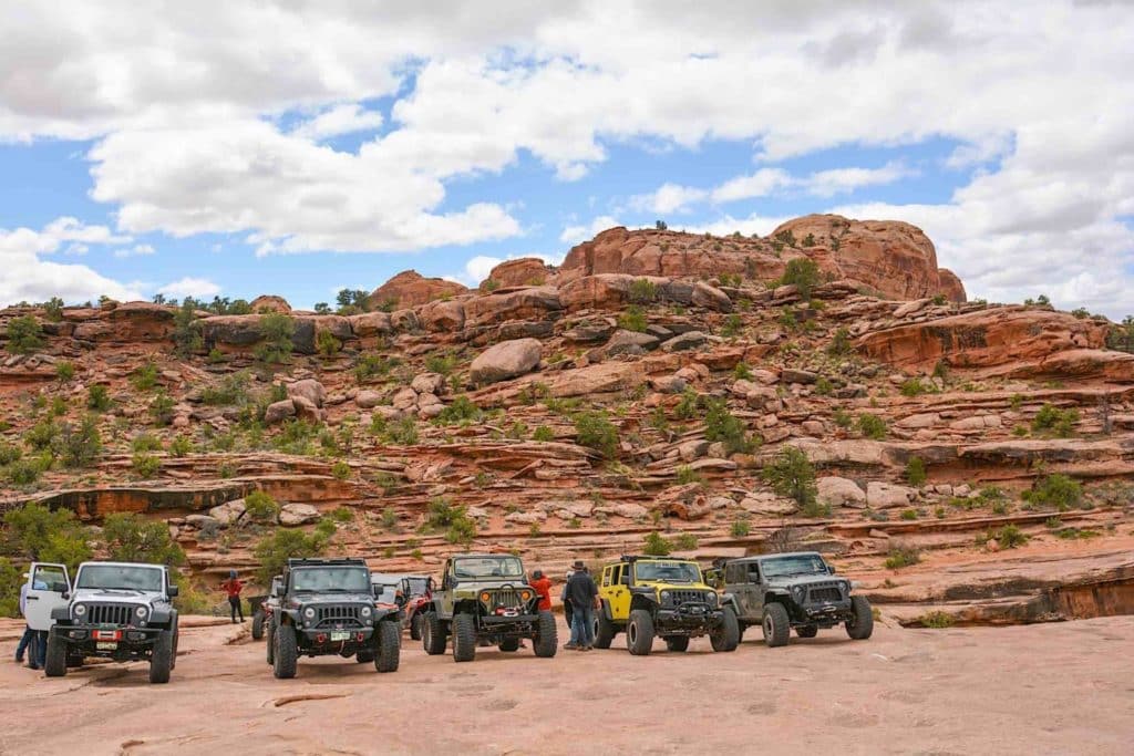 Several jeeps stopped on a trail near a plateau.