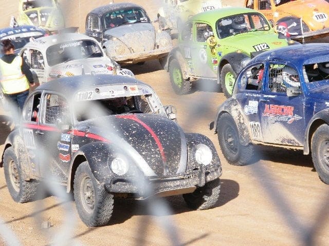 VW Bettles racing down a dirt track.