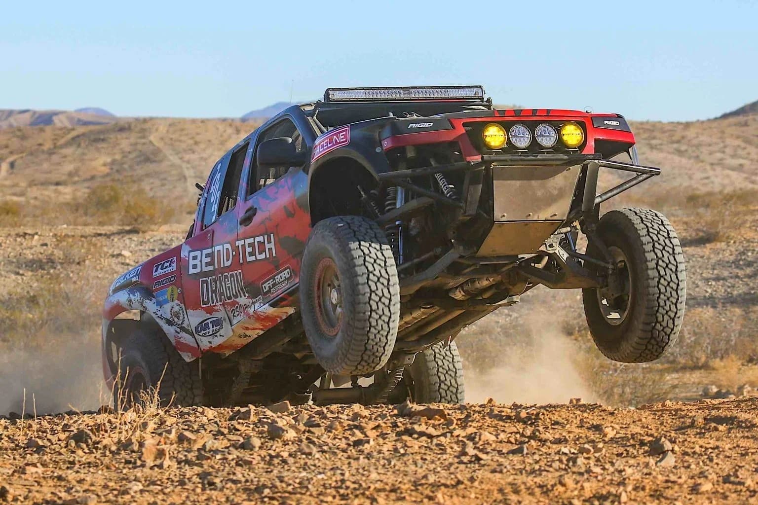 A racing truck leaping off a hill ramp