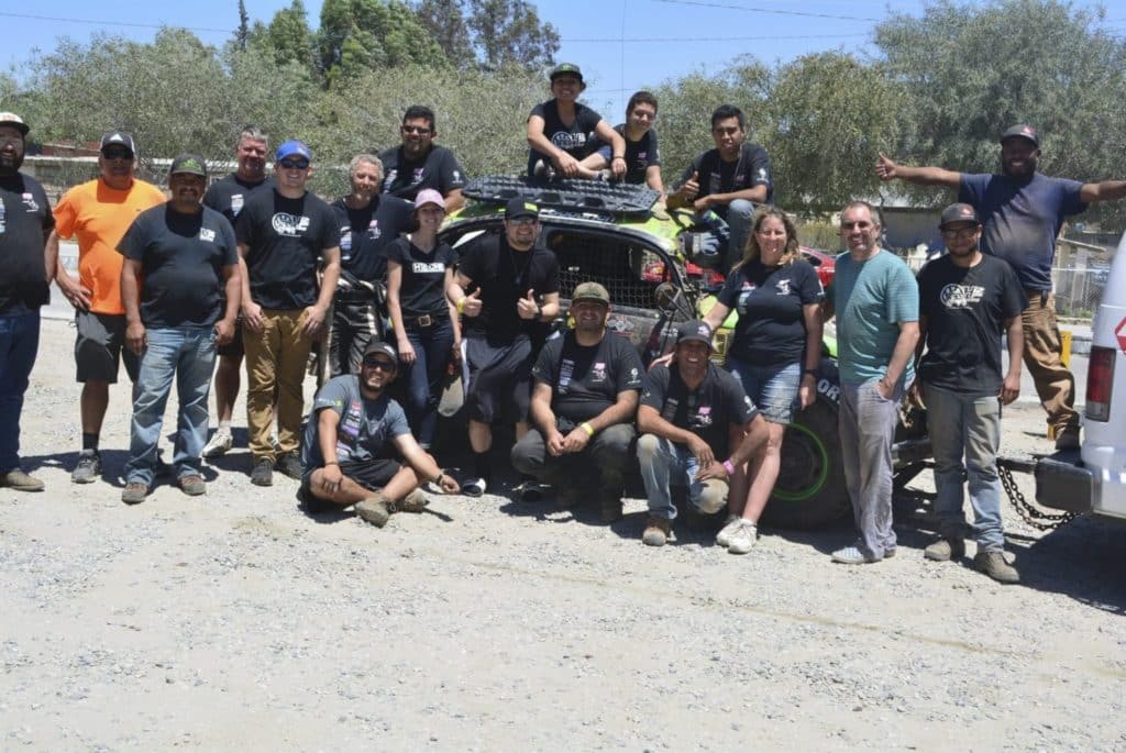 A group of people standing on a dirt track.