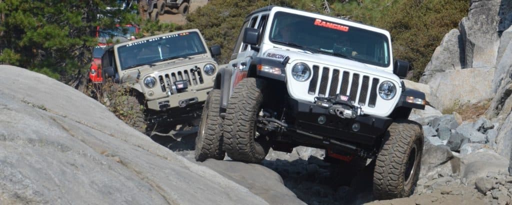 A caravan of Jeeps driving over rocky terrain.