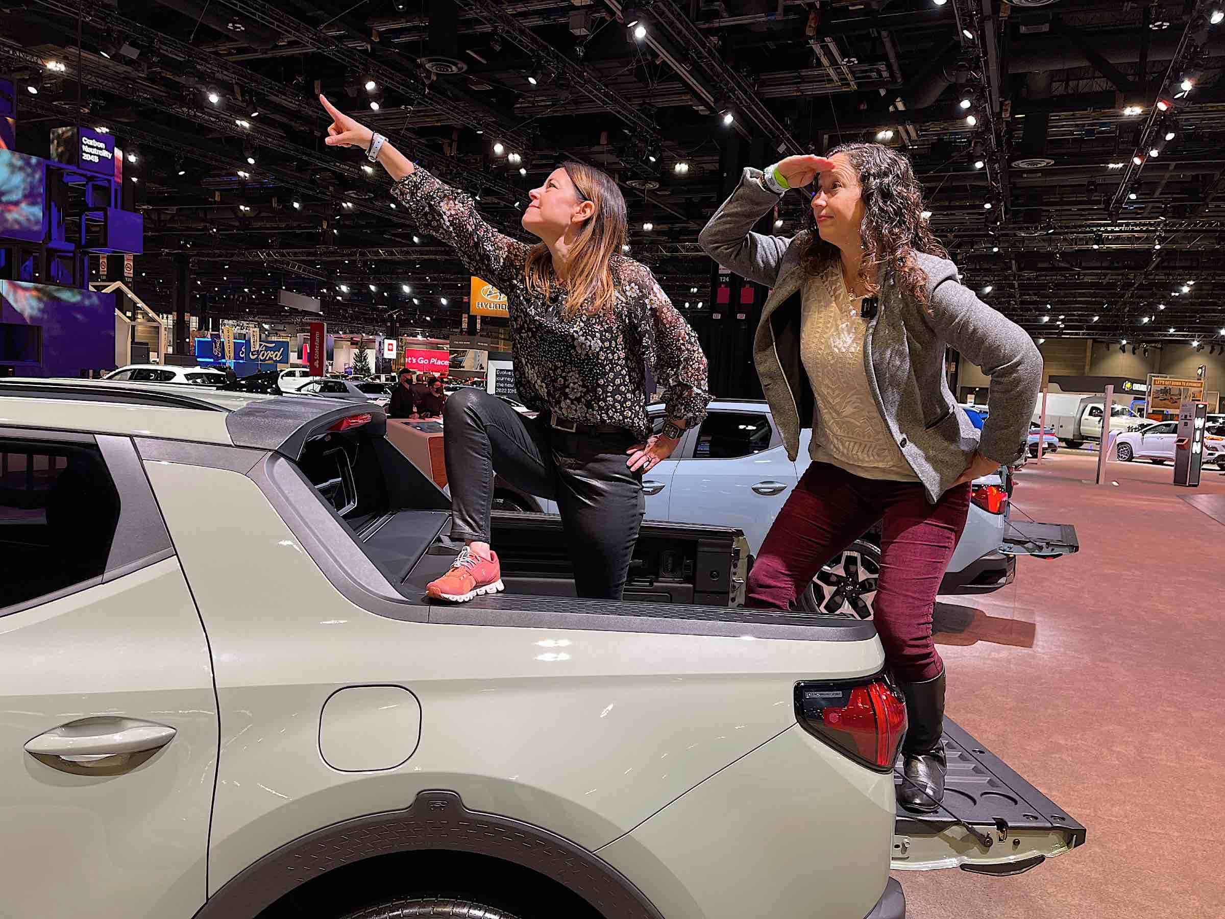 Two women stand in the back of a Hyundai Santa Cruz