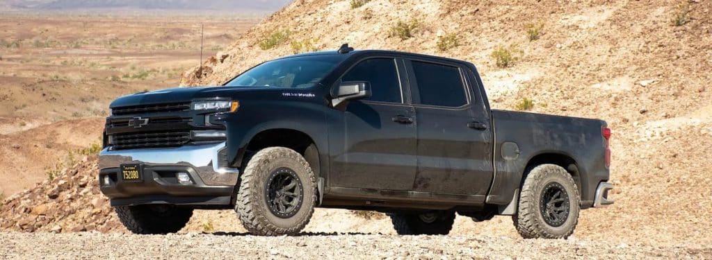 A black Chevrolet truck on a rocky road.