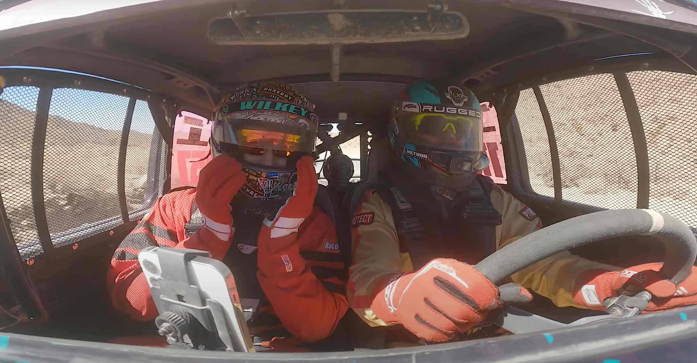 A driver behind the wheel of a racing truck.