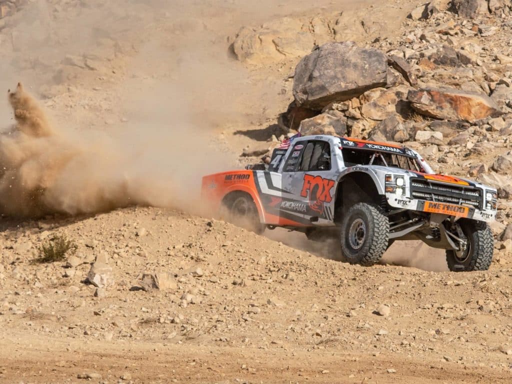 A racing truck on a dirt and rocky track.