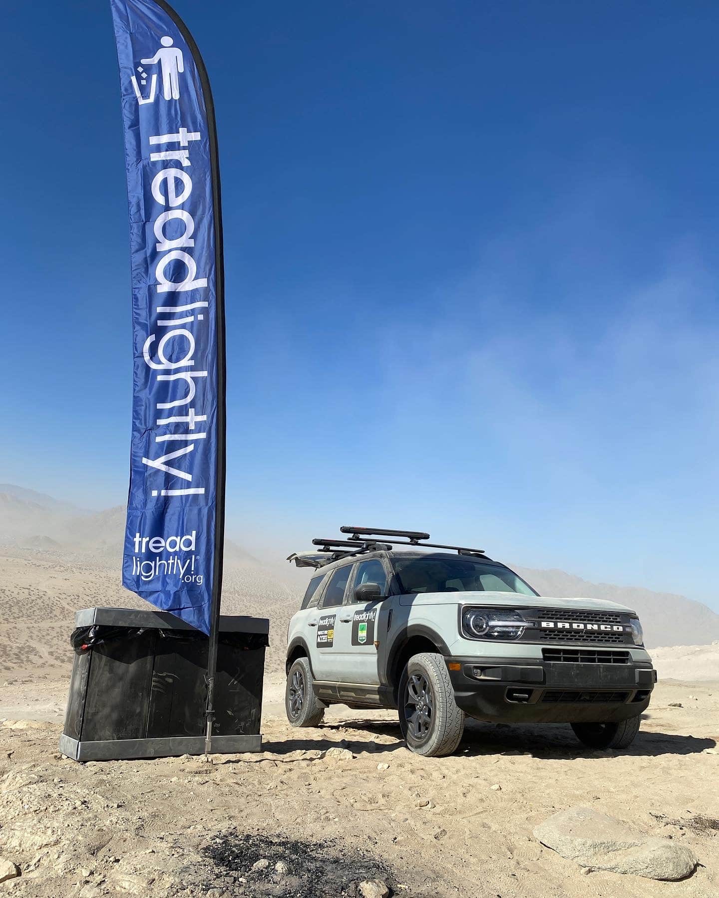 A Ford Bronco SUV parked next to a Tread Lightly banner flag.