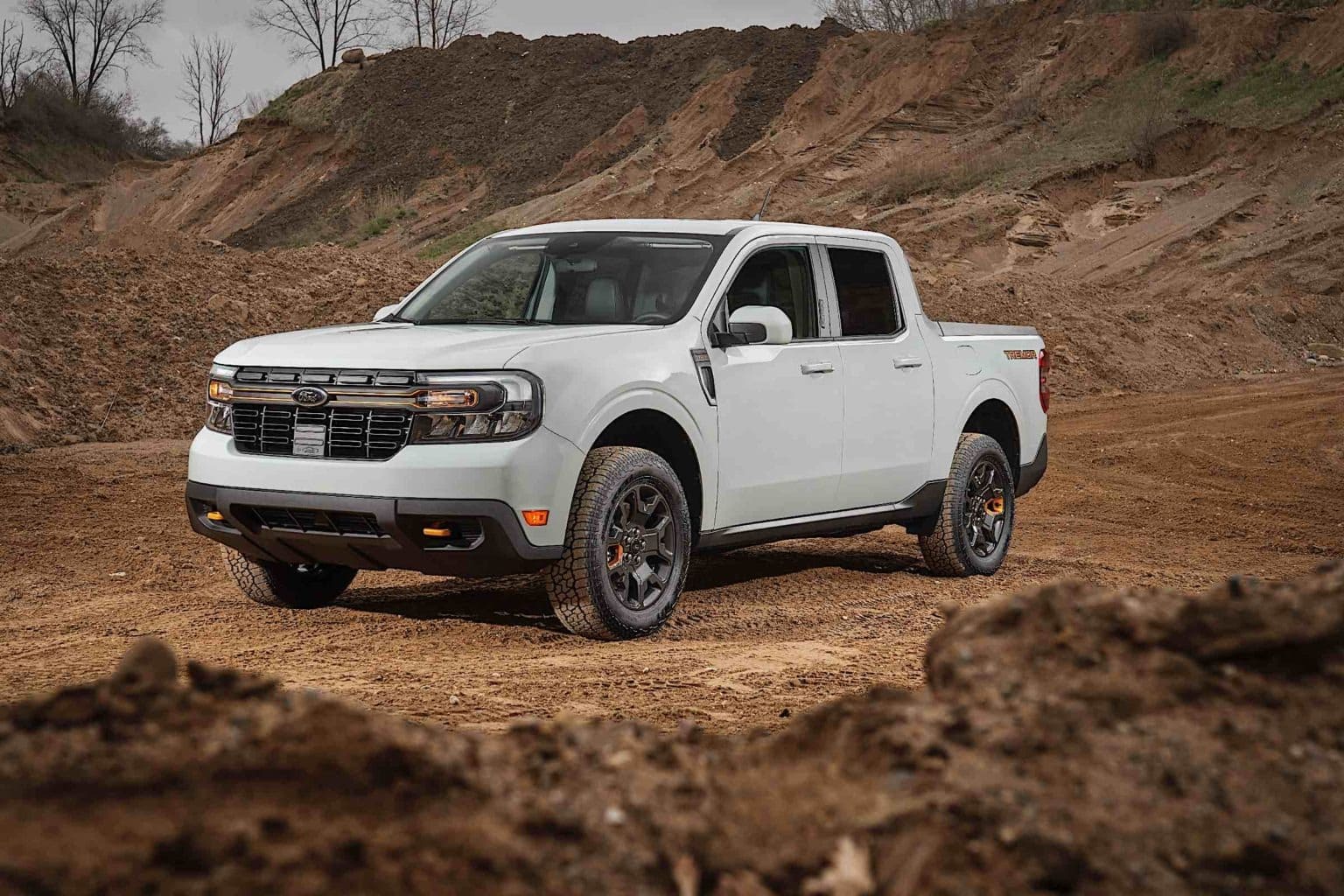 A 2023 Ford Maverick truck sitting on a dirt, mud, and rocky terrain.