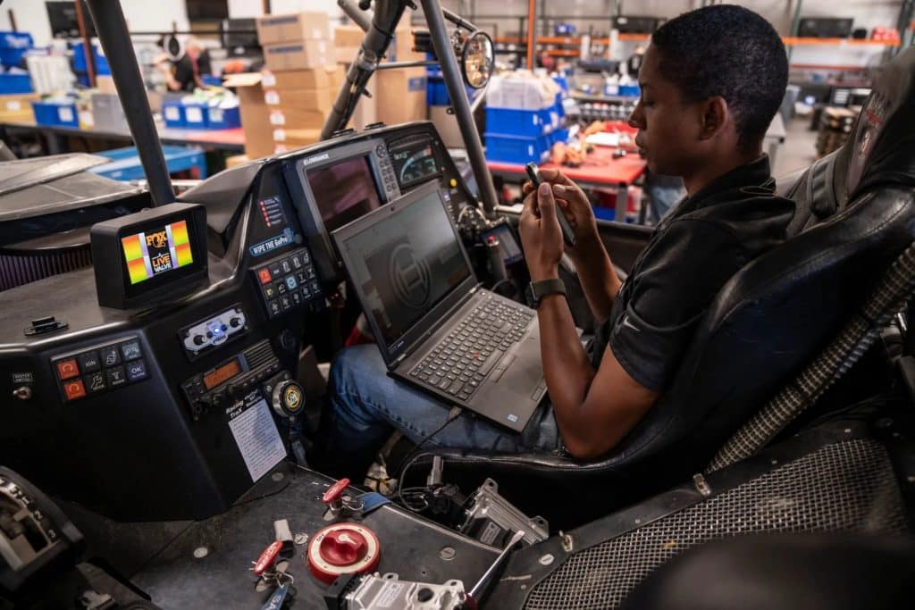 A man sits in a racing truck cab.