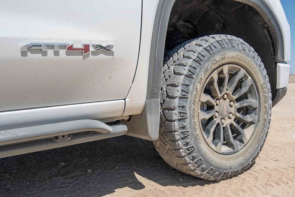 A GMC Sierra AT4X driving across rocky desert terrain.