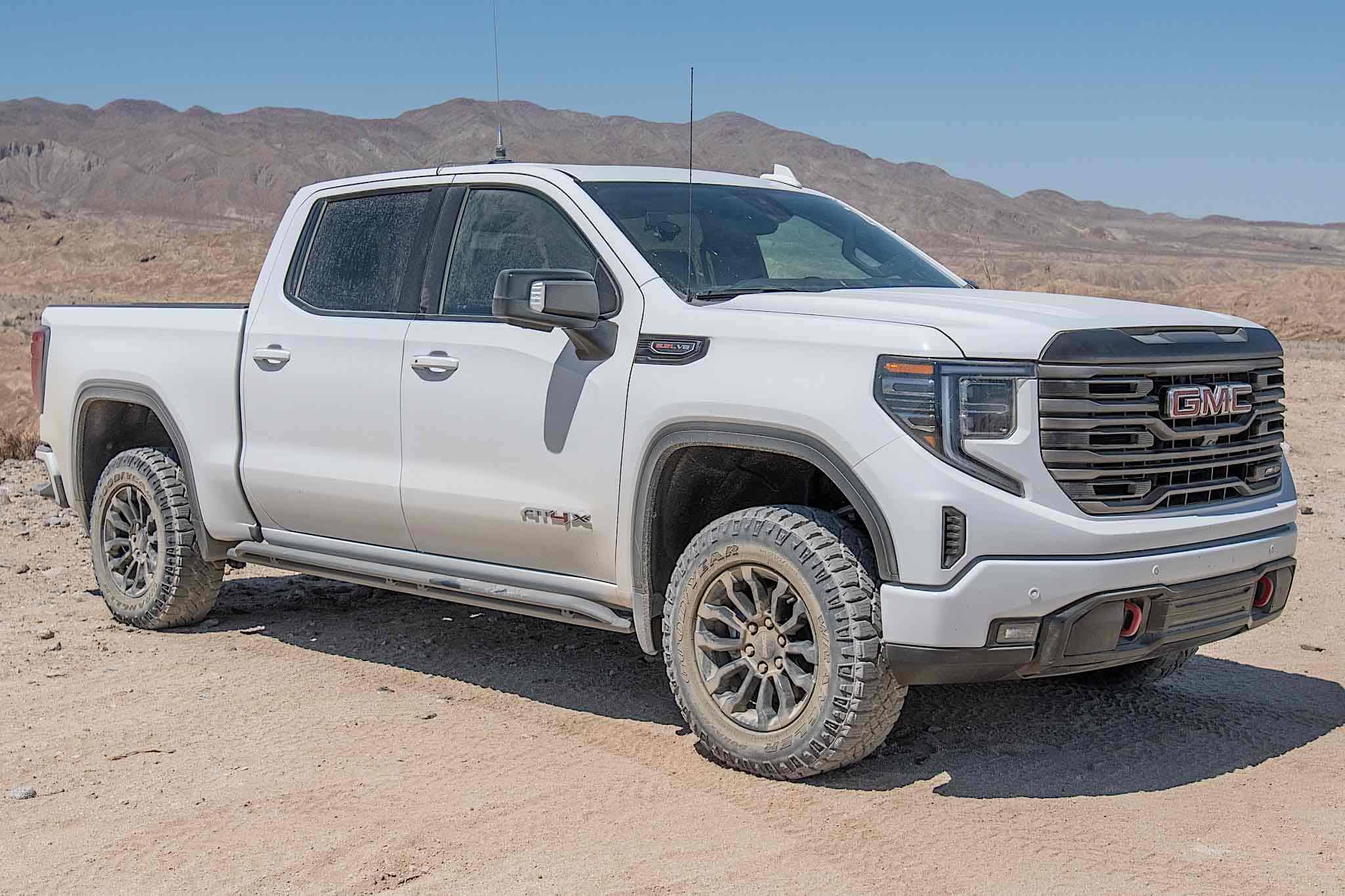 A GMC Sierra AT4X driving across rocky desert terrain.