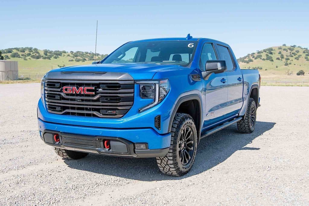 A GMC Sierra AT4X driving across rocky desert terrain.