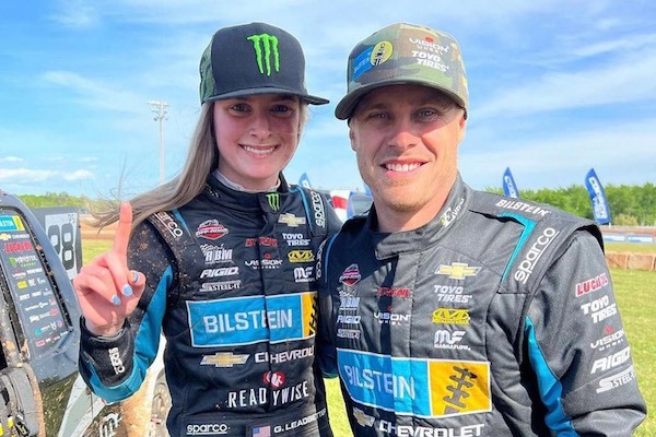 Two off-road racers smiling and pose for a camera.