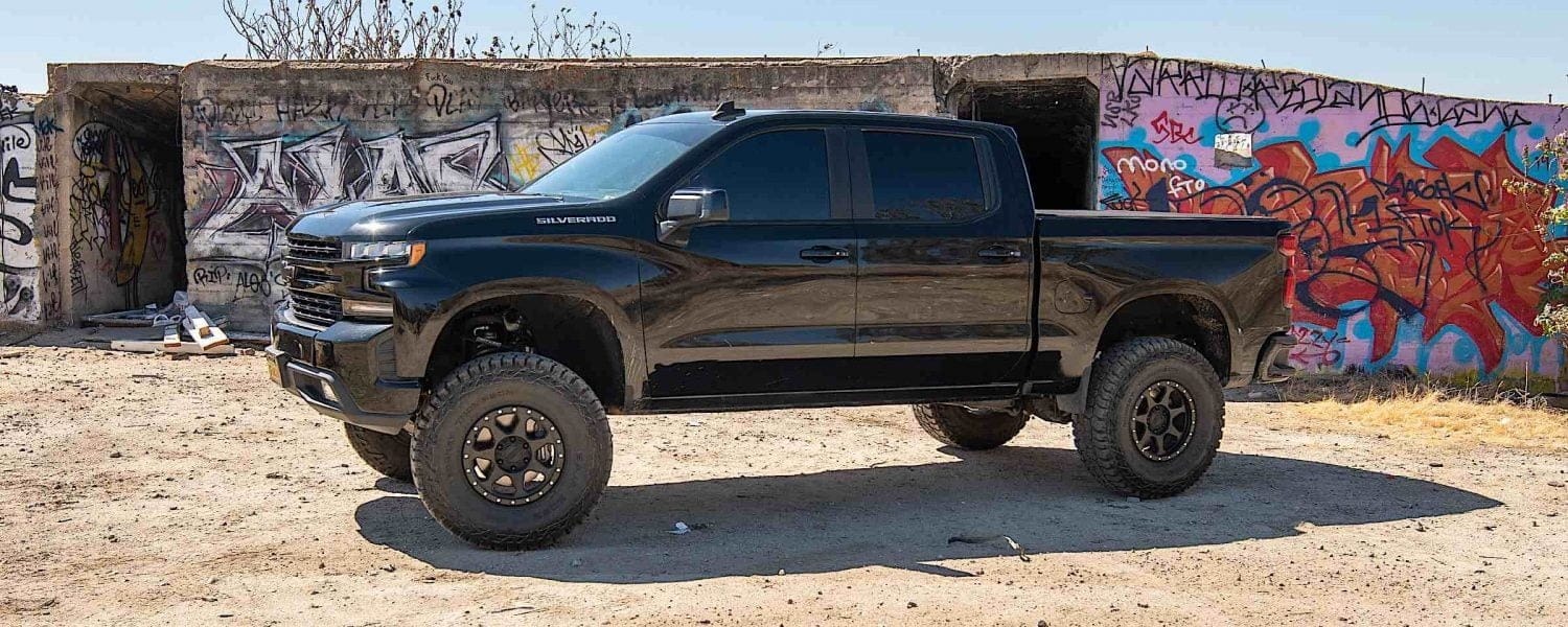 A 2019 Chevrolet Silverado on a dirt and rocky terrain in front of storage containers.