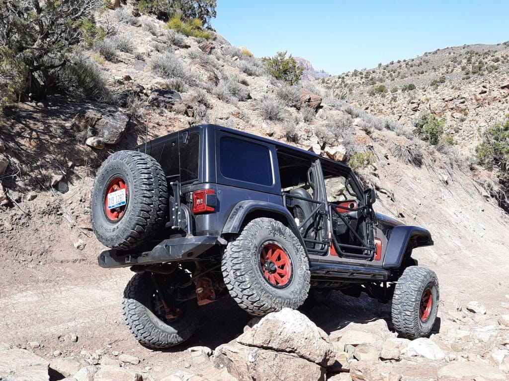 A jeep driving over rocky and dirt terrain.