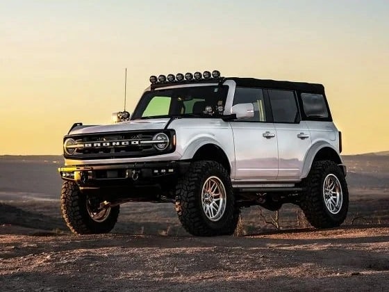 A Jeep Bronco on the desert at sunset.