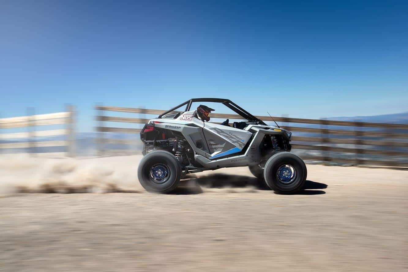 A Polaris RZR Turbo R racing across the dirt.