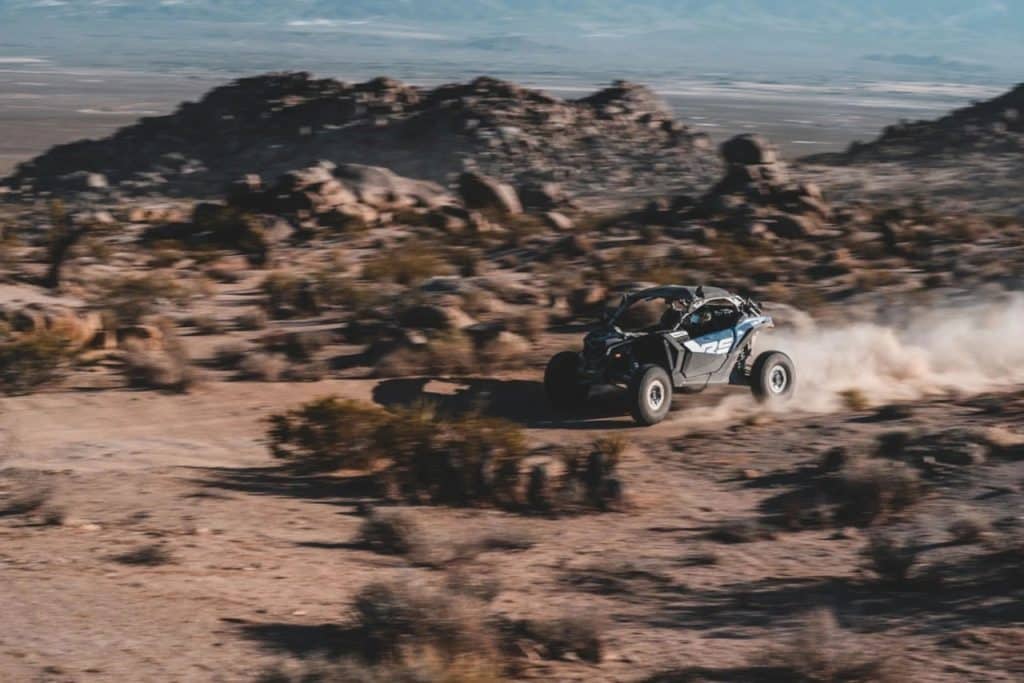 A Can-Am driving through the desert.