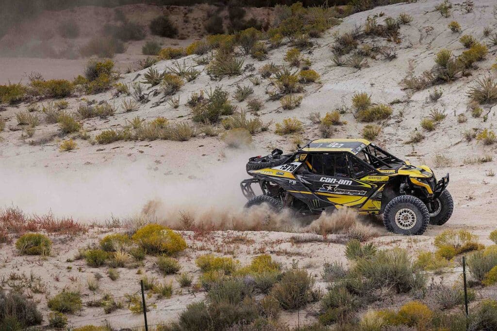 A UTV racing across the dusty desert race track.